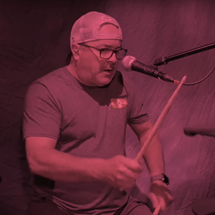 man holding drum sticks as if playing the drums in front of a canvas-like backdrop