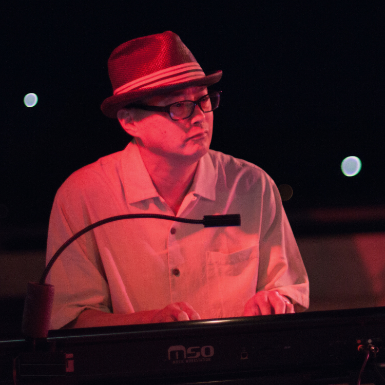 man wearing a stylist hat and glasses playing the keyboards