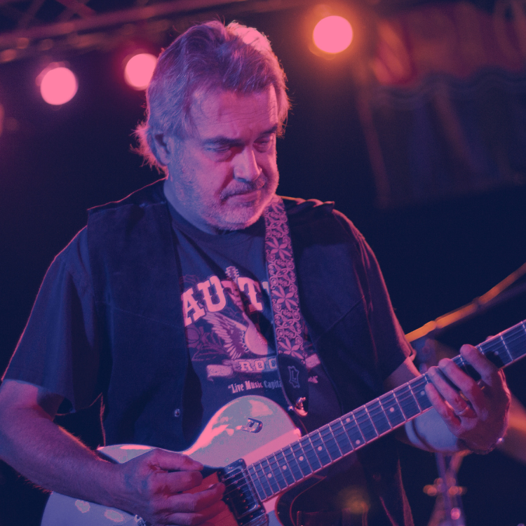 stage lights shining behind a man playing an electric guitar