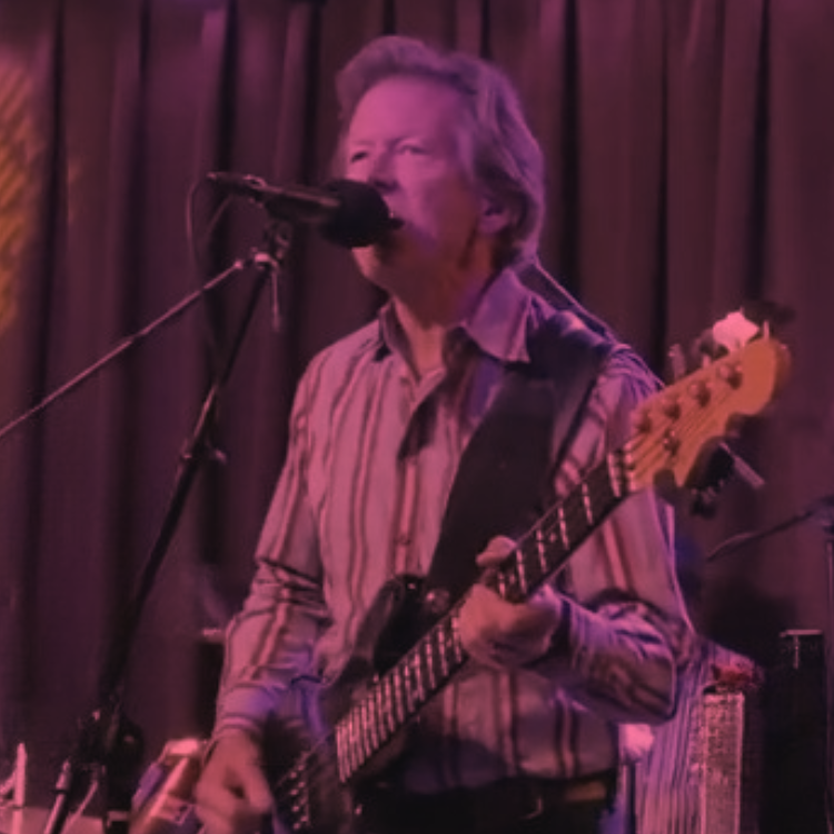 curtain backdrop behind a man playing a bass guitar and singing into a microphone